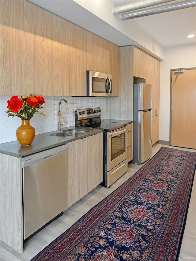603 Inca St Unit 429, Denver, CO 80204 - kitchen with appliances with stainless steel finishes, light brown cabinetry, a sink, modern cabinets, and decorative backsplash