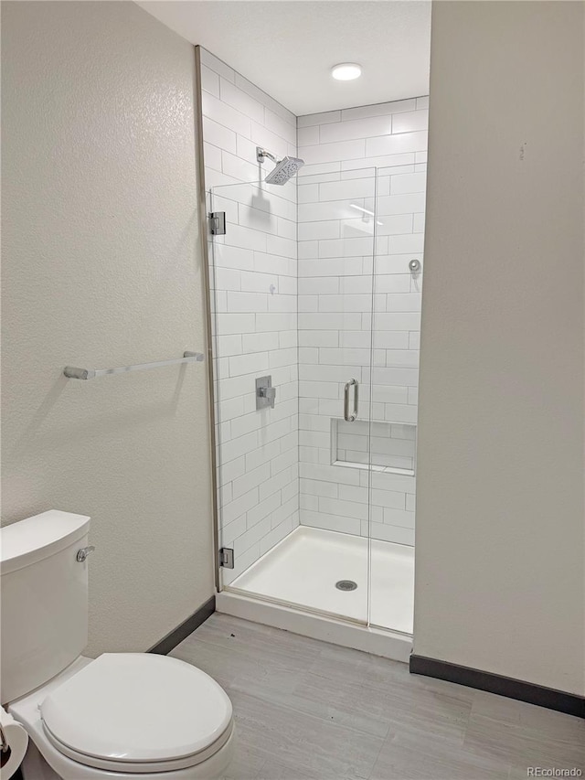 603 Inca St Unit 429, Denver, CO 80204 - full bathroom with toilet, a shower stall, baseboards, and wood finished floors