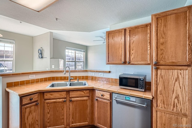 7440 S Blackhawk St Unit 4-102, Englewood, CO 80112 - kitchen featuring a sink, stainless steel appliances, tile counters, a peninsula, and a textured ceiling