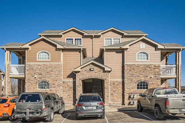 7440 S Blackhawk St Unit 4-102, Englewood, CO 80112 - view of property featuring stone siding, uncovered parking, and a balcony