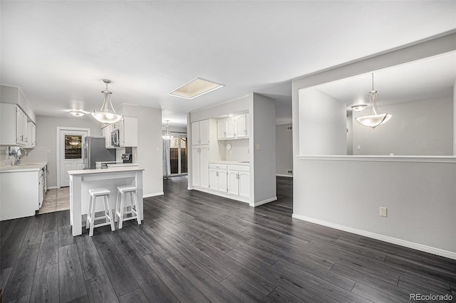 8022 W 78th Way, Arvada, CO 80005 - kitchen featuring white cabinets, light countertops, dark wood-style floors, and a kitchen bar