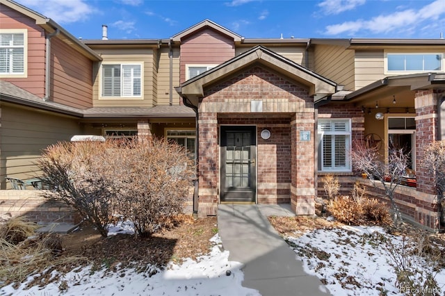 snow covered property entrance with brick siding