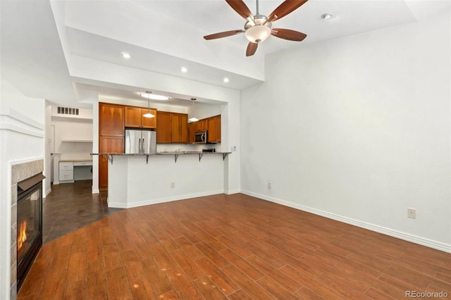 unfurnished living room featuring dark wood-style floors, baseboards, and a tiled fireplace