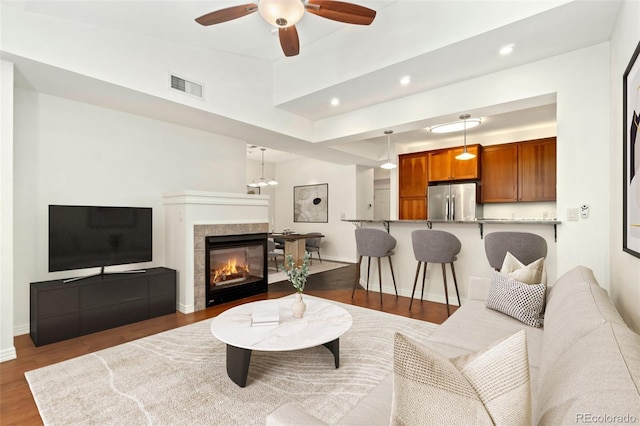 living room with a tile fireplace, recessed lighting, visible vents, baseboards, and dark wood finished floors