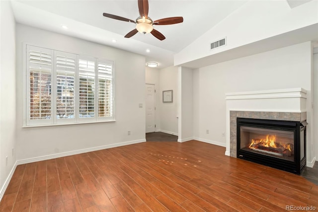 unfurnished living room with lofted ceiling, visible vents, a tiled fireplace, wood finished floors, and baseboards