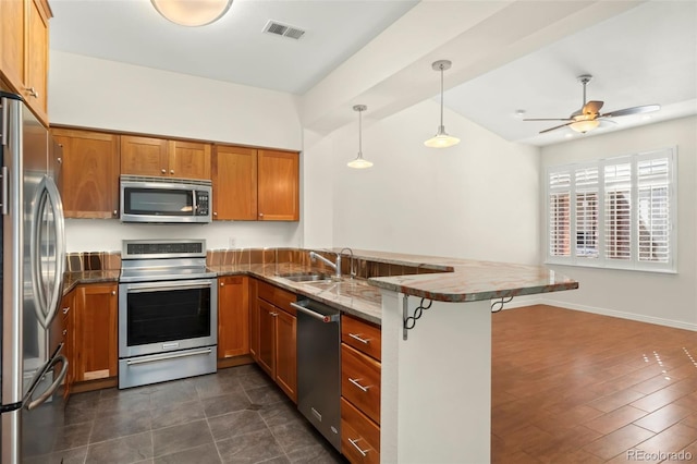 kitchen featuring visible vents, a breakfast bar, decorative light fixtures, a peninsula, and stainless steel appliances