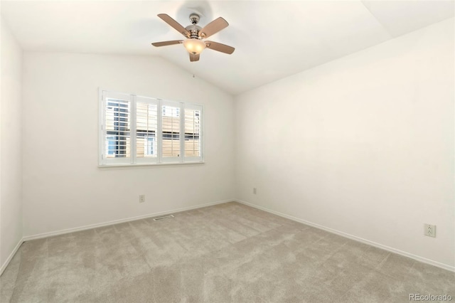 spare room with light carpet, baseboards, and vaulted ceiling