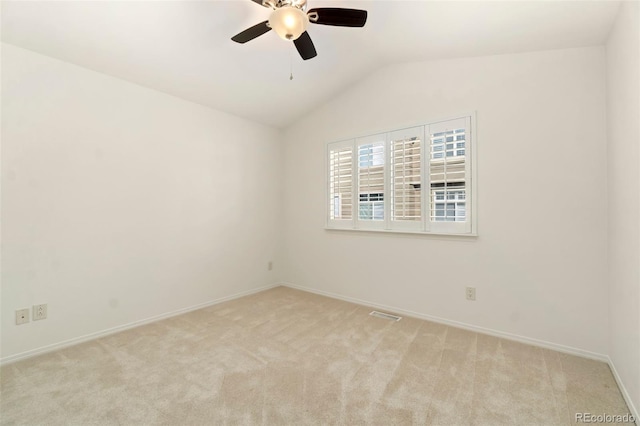 spare room featuring lofted ceiling, light carpet, ceiling fan, and baseboards