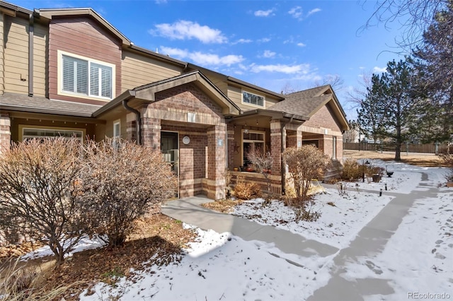 craftsman inspired home featuring brick siding, fence, and roof with shingles