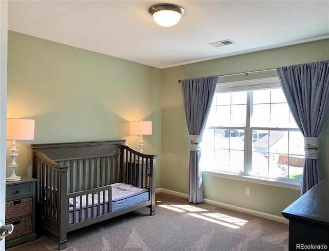 bedroom featuring carpet flooring, a crib, and multiple windows