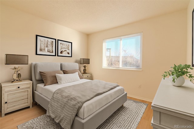 bedroom featuring a textured ceiling and light hardwood / wood-style flooring