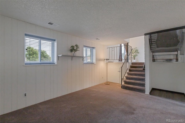 2493 S Kalispell Cir, Aurora, CO 80013 - unfurnished living room featuring carpet floors, stairs, a textured ceiling, and wood walls