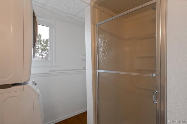 2493 S Kalispell Cir, Aurora, CO 80013 - full bath with stacked washer and clothes dryer, a shower with shower door, a drop ceiling, and wood finished floors