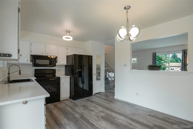 2493 S Kalispell Cir, Aurora, CO 80013 - kitchen with black appliances, light countertops, white cabinetry, light wood finished floors, and a chandelier