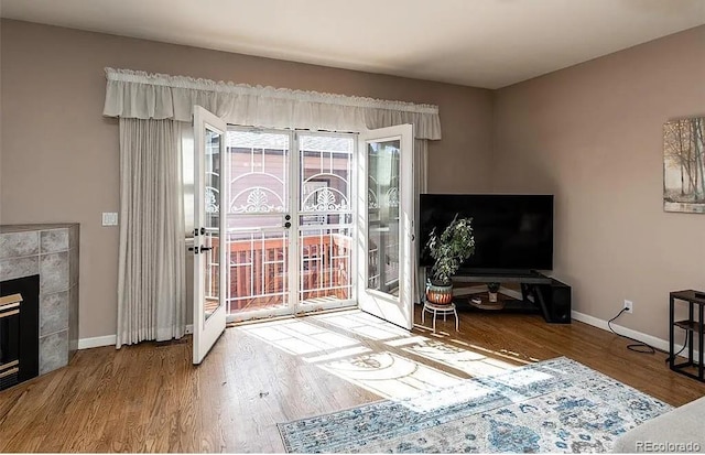 living room featuring a tiled fireplace, wood finished floors, and baseboards