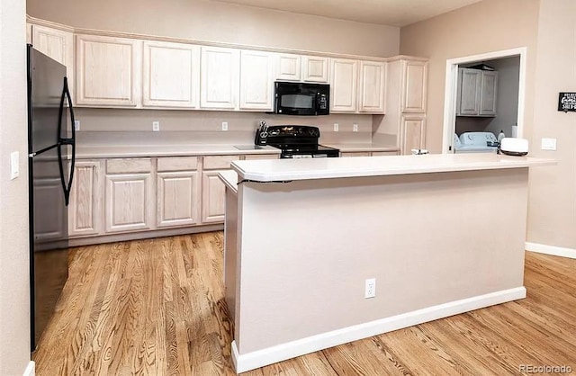 kitchen with black appliances, light wood-style flooring, light countertops, and washing machine and clothes dryer