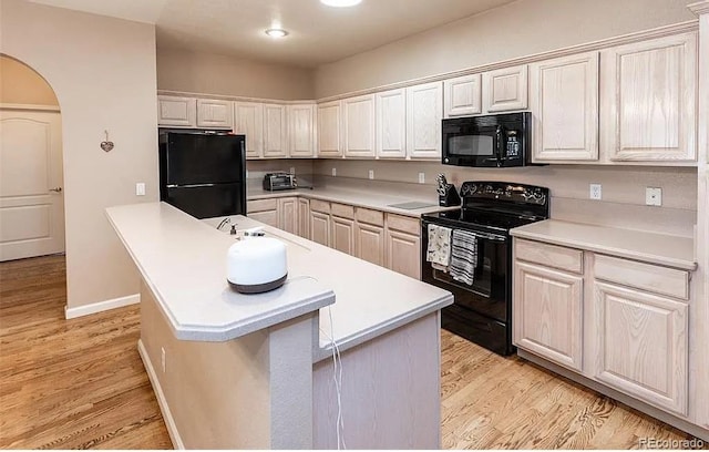 kitchen featuring light wood-style floors, arched walkways, light countertops, and black appliances