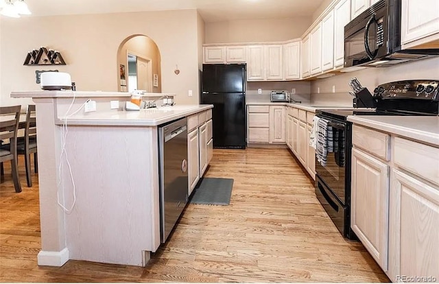 kitchen with black appliances, a kitchen island, light countertops, and light wood finished floors