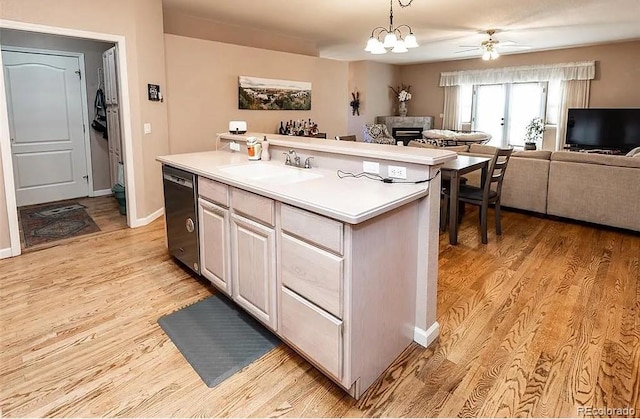 kitchen featuring a sink, open floor plan, light countertops, light wood-type flooring, and dishwasher