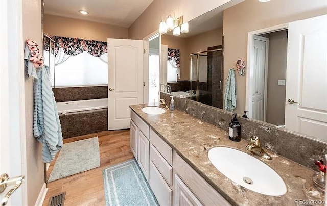 bathroom featuring wood finished floors, a sink, visible vents, and a shower stall