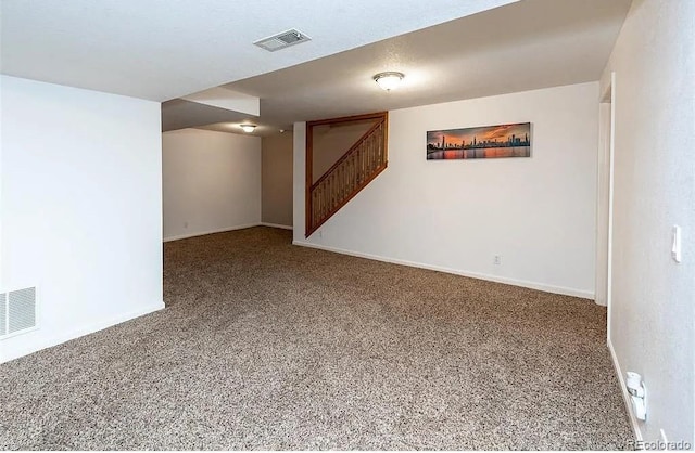 finished below grade area featuring carpet floors, baseboards, stairs, and visible vents