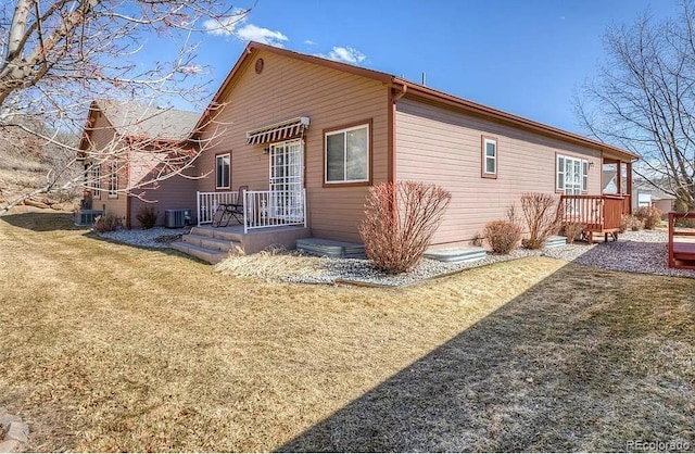 back of property featuring central AC and a lawn