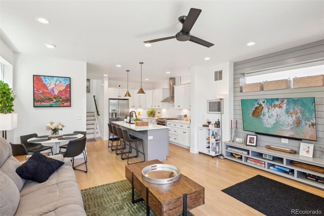 1299 Newton St, Denver, CO 80204 - living area featuring a ceiling fan, stairway, light wood-style floors, and recessed lighting