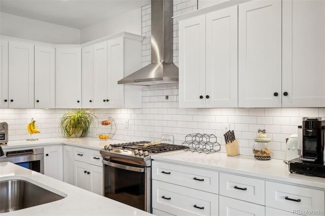 1299 Newton St, Denver, CO 80204 - kitchen featuring stainless steel gas range oven, wall chimney range hood, white cabinets, and backsplash