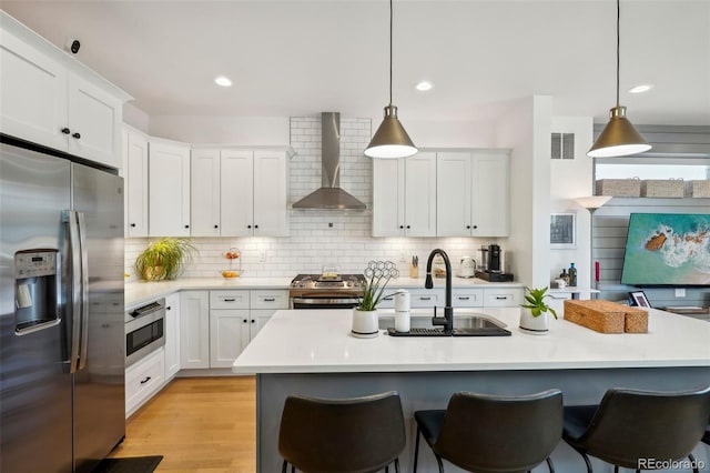 1299 Newton St, Denver, CO 80204 - kitchen featuring stainless steel appliances, wall chimney exhaust hood, a sink, a kitchen breakfast bar, and light countertops