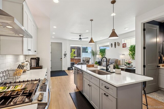 1299 Newton St, Denver, CO 80204 - kitchen featuring a sink, wall chimney range hood, appliances with stainless steel finishes, light countertops, and recessed lighting
