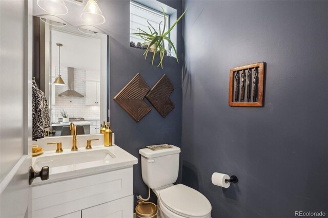 1299 Newton St, Denver, CO 80204 - bathroom featuring toilet, vanity, and backsplash