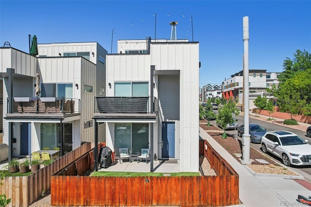 1299 Newton St, Denver, CO 80204 - rear view of property featuring a fenced front yard, board and batten siding, a balcony, and a residential view
