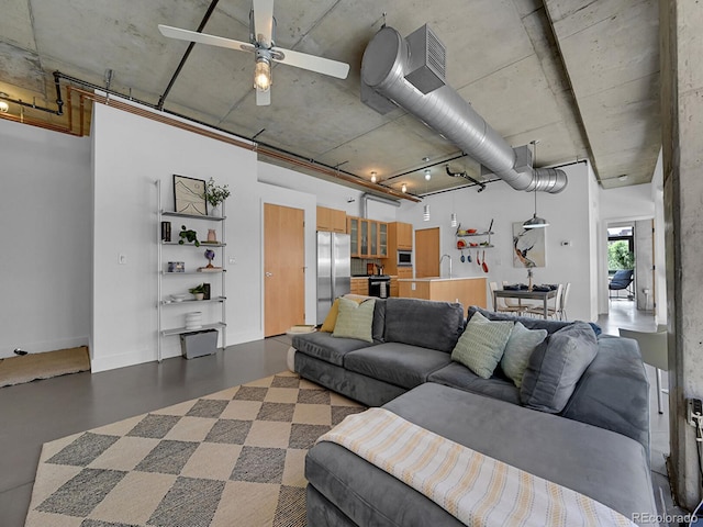 living room with a ceiling fan and concrete flooring