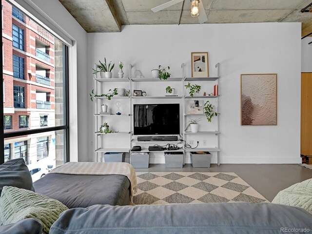 living room featuring a ceiling fan and finished concrete floors