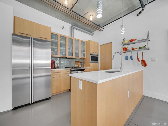 kitchen with appliances with stainless steel finishes, a sink, a peninsula, backsplash, and glass insert cabinets