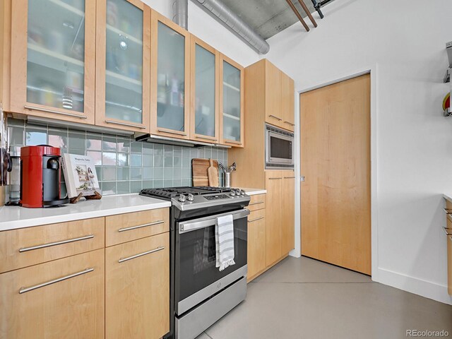 kitchen with appliances with stainless steel finishes, tasteful backsplash, light countertops, light brown cabinetry, and glass insert cabinets
