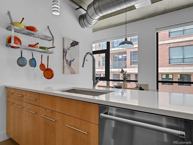 kitchen featuring dishwasher, a sink, light countertops, and decorative light fixtures