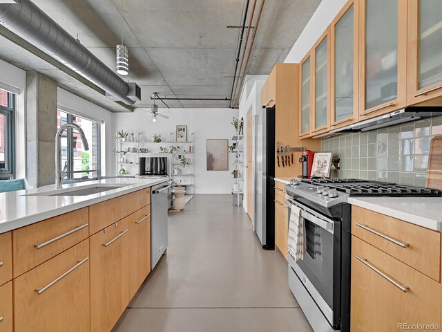 kitchen featuring appliances with stainless steel finishes, a sink, backsplash, and light countertops