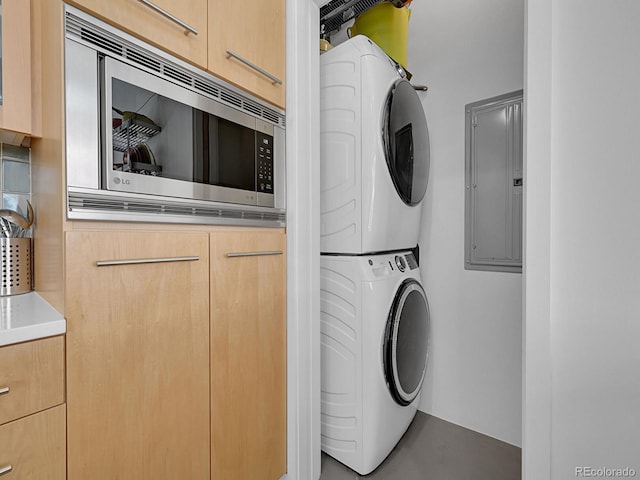 laundry room with stacked washer and clothes dryer, electric panel, and cabinet space