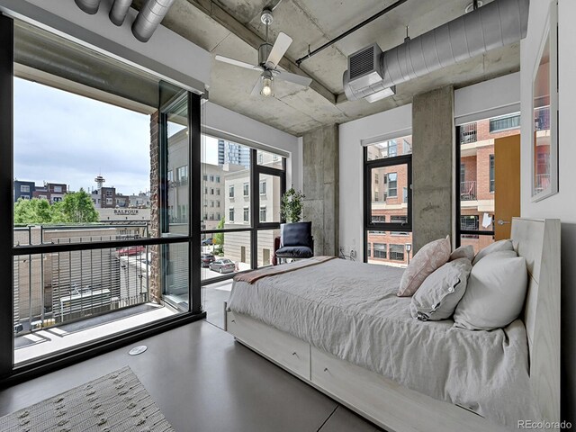 bedroom featuring finished concrete floors, ceiling fan, and a view of city
