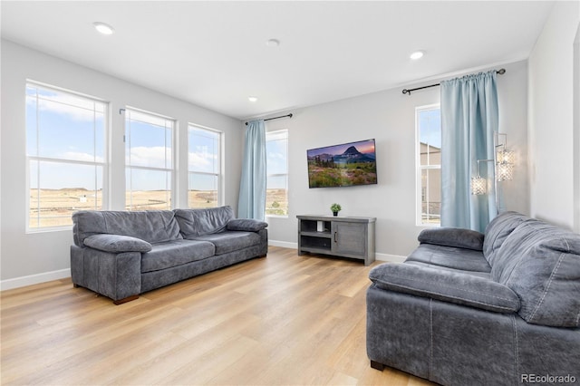 living room with a healthy amount of sunlight, baseboards, recessed lighting, and light wood-style flooring