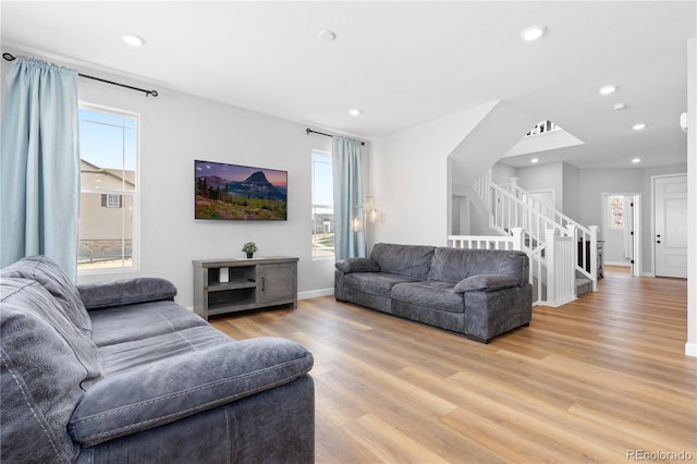 living area with recessed lighting, a healthy amount of sunlight, light wood finished floors, and stairway