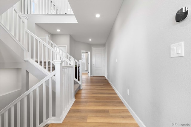 hallway with recessed lighting, baseboards, light wood finished floors, and stairs