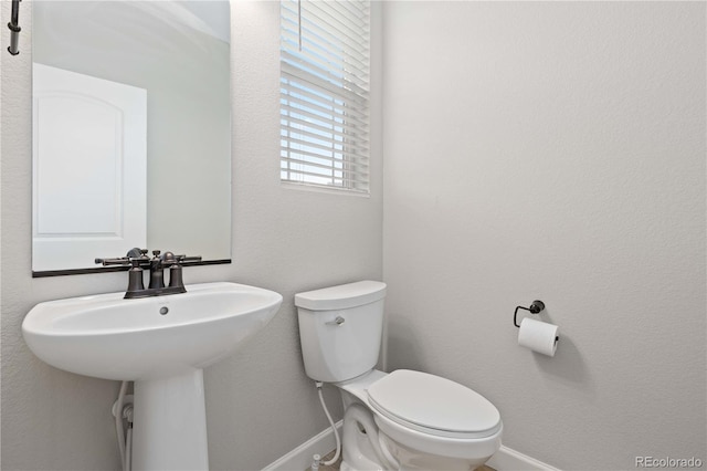 bathroom featuring baseboards, a sink, and toilet
