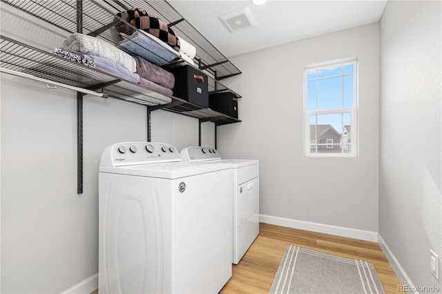 washroom featuring laundry area, baseboards, separate washer and dryer, and light wood-style floors