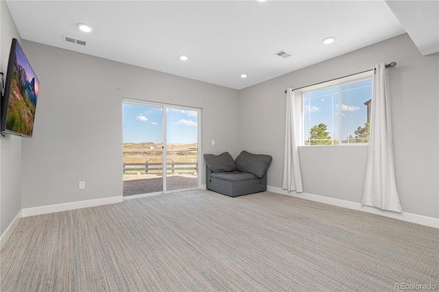 unfurnished room featuring baseboards, a wealth of natural light, carpet, and visible vents