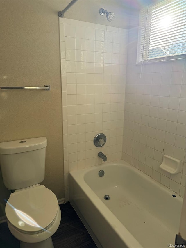 bathroom featuring tiled shower / bath combo and toilet