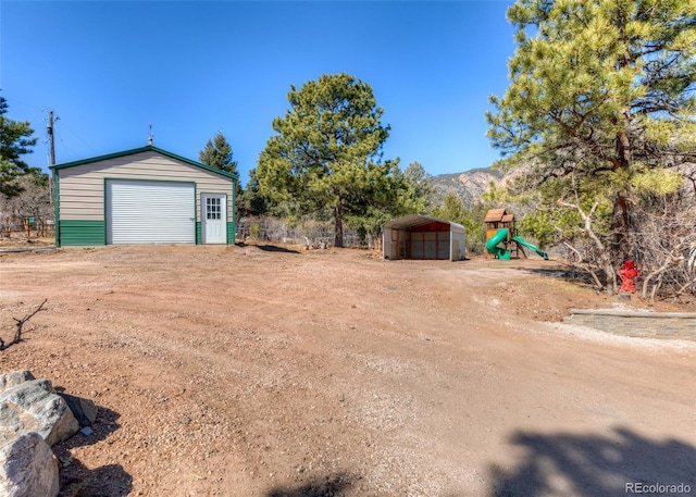 630 Rock Creek Mesa Rd, Colorado Springs, CO 80926 - view of yard featuring an outbuilding, driveway, a detached garage, a playground, and a mountain view