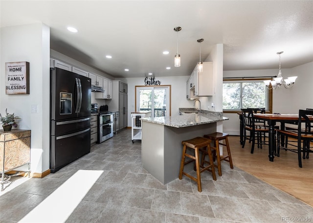 630 Rock Creek Mesa Rd, Colorado Springs, CO 80926 - kitchen featuring light stone counters, a peninsula, range with two ovens, plenty of natural light, and black refrigerator with ice dispenser
