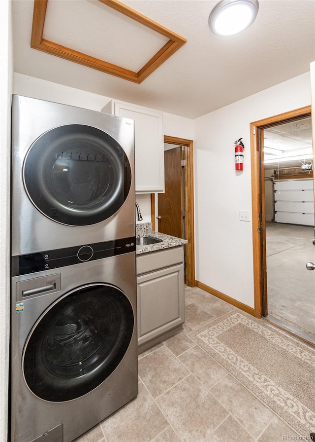 630 Rock Creek Mesa Rd, Colorado Springs, CO 80926 - washroom featuring a sink, stacked washer / drying machine, baseboards, and cabinet space
